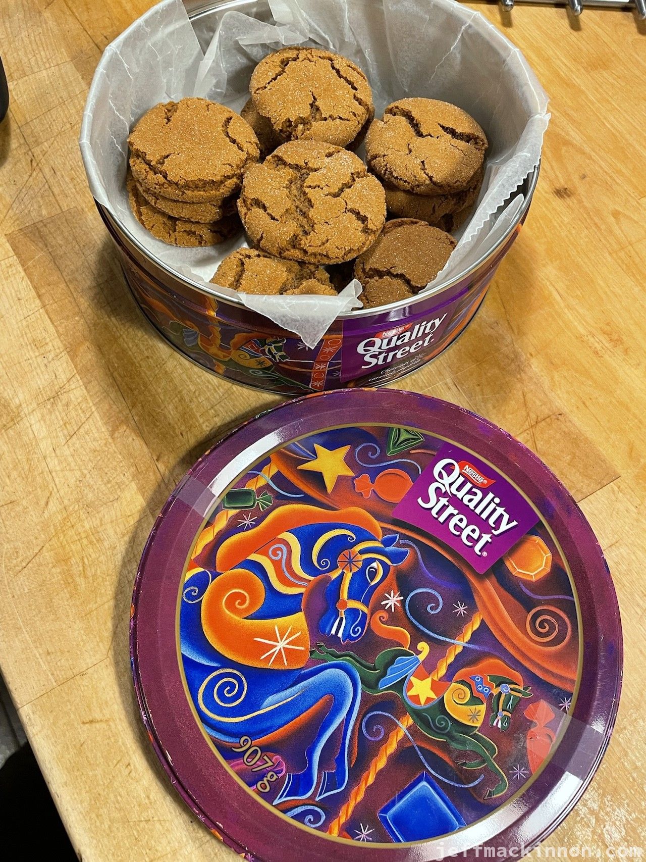 A round Quality Street tin filled with cookies.